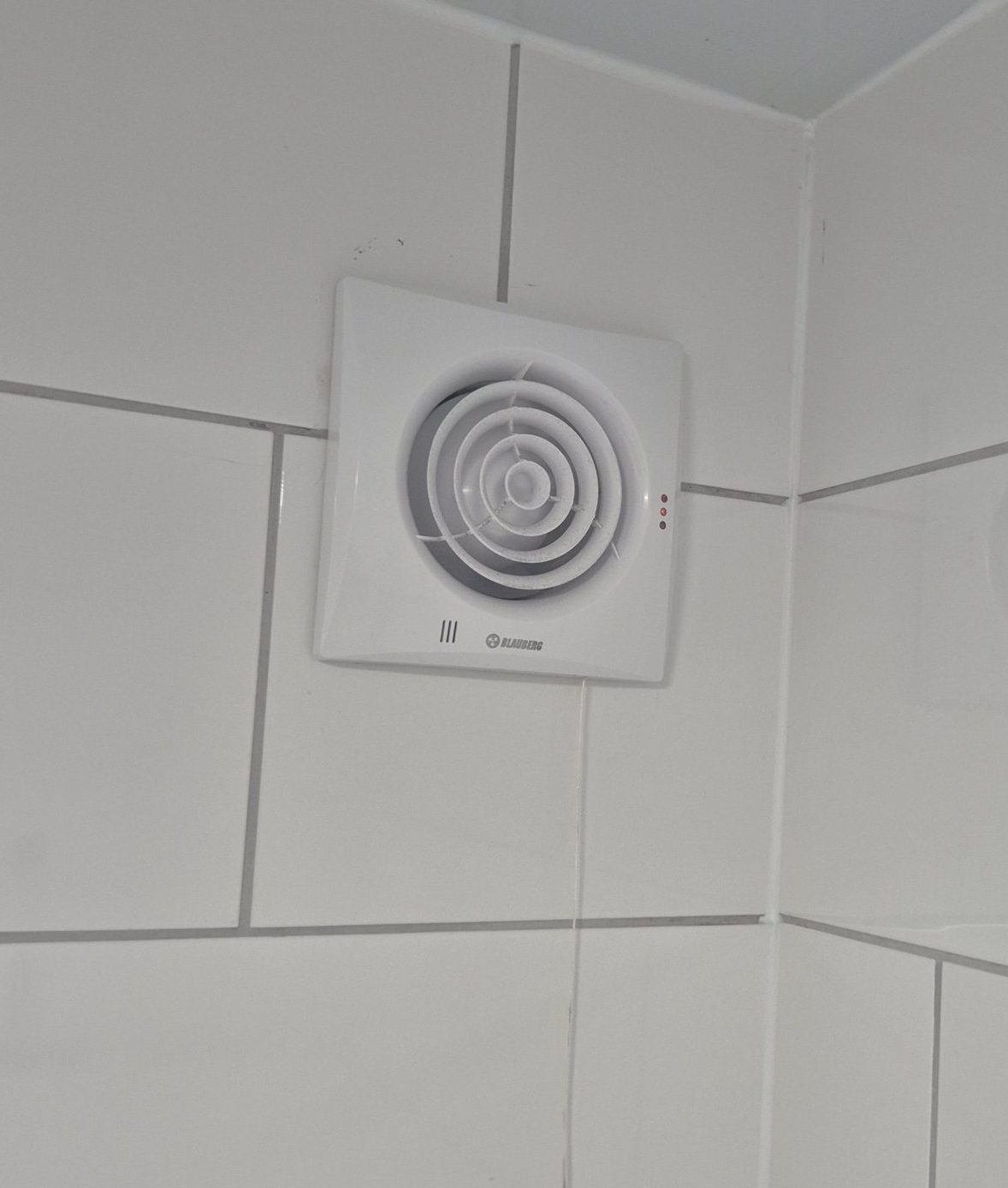 Electrical extractor fan installed in bathroom on white tiles by HudsonsElec in Liverpool